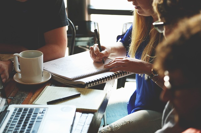 A group of writers sitting around a table with a notebook and coffee